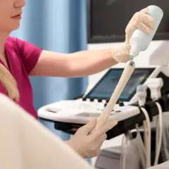 Lekarka przygotowuje sondę USG do badania, aplikując żel. Badanie pozwala ocenić stan endometrium po menopauzie.