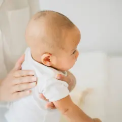 Delikatne odbijanie noworodka, jego mała główka opiera się o ramię rodzica.