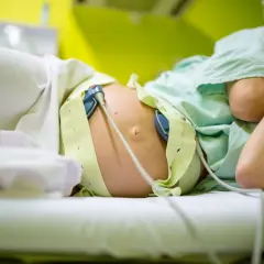 Brzuch ciężarnej z czujnikami KTG, monitorującymi skurcze przepowiadające przed porodem.