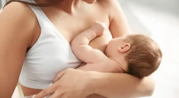 Matka karmi piersią dziecko. Widoczny jest nawał pokarmu, który jest naturalnym etapem laktacji.