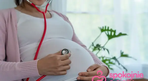Kobieta w 27 tygodniu ciąży, który to miesiąc, słucha bicia serca dziecka przez stetoskop.