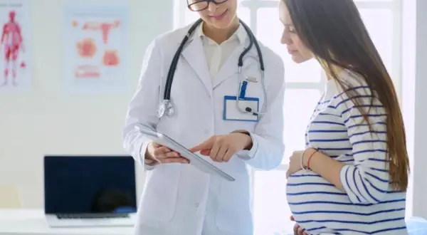 Lekarka omawia z ciężarną pacjentką znaczenie luteiny w ciąży, wskazując na tablet.