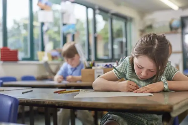 Dziewczynka w szkole rysuje, skupiona na pracy. Czy to zadanie od jakiej średniej jest 2?